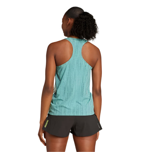 En kvinde står med ryggen til kameraet i en powtea/pretea Adidas Adizero Singlet, Dame og sorte shorts. Hendes krøllede hestehale og den hvide baggrund fremhæver denne ultralette løbetøj.