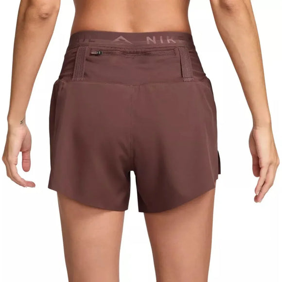 En person ses bagfra iført Nike Dri-FIT Trail Mid-Rise 4" Brief-Lined Running Shorts til kvinder i Red Sepia/Black med en lille lynlåslomme nær linningen. Baggrunden er hvid.
