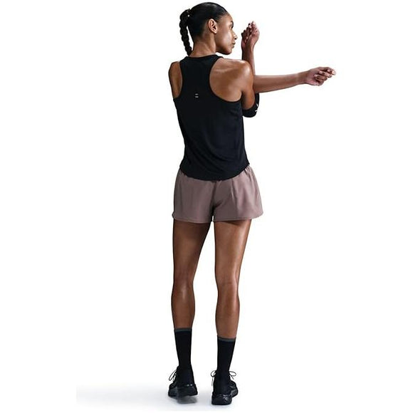 En person iført Nike Tempo Dri-FIT Running Tank Top, Dame, Black, brune shorts, sorte sokker og sorte sko står med ryggen til, mens han strækker sin venstre arm over brystet.