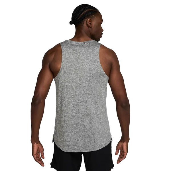 En person med flettet hår ses bagfra iført en Nike Stride Running Tank til mænd i Smoke Grey/Htr/Reflective Silv og sorte shorts på en almindelig hvid baggrund.
