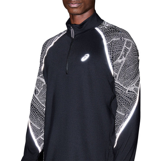 En person iført Asics Limited Series Lite-Show Ls Top, Herre, Performance Black-en svedtransporterende trøje med hvide refleksdetaljer og geometrisk mønster på ærmerne. Asics-logo ses på brystet; ansigt delvist udenfor billedet.