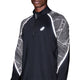 En person iført Asics Limited Series Lite-Show Ls Top, Herre, Performance Black-en svedtransporterende trøje med hvide refleksdetaljer og geometrisk mønster på ærmerne. Asics-logo ses på brystet; ansigt delvist udenfor billedet.