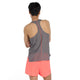 En person med kort sort hår står med armene over kors og kigger væk, iført New Balance Race Day Ultra Light Singlet, Herre, i Urgent Red. De parrer den med lyse koralfarvede shorts mod en almindelig hvid baggrund.