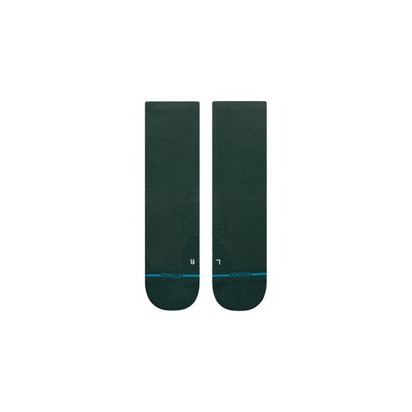 Et par Stance Run Light Crew unisex-strømper i fyrretræsgrøn, med anatomisk pasform med L- og R-markeringer nær tåen og en tynd blå linje over, er lagt fladt side om side på en almindelig hvid baggrund.