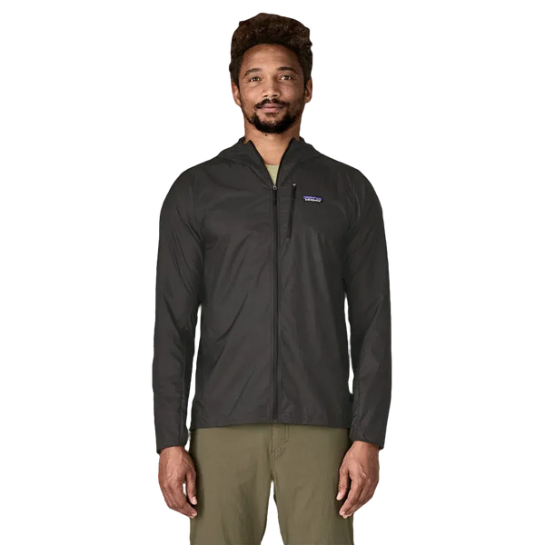 En mand kigger fremad mod en hvid baggrund iført Patagonias Houdini Jacket, Herre, Black w/Black og olivengrønne bukser.