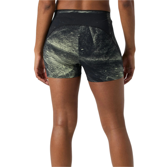 En person ses bagfra iført On's Race Tights Short, Dame, i Black/Limelight. Fokus er på de højtaljede løbeshorts med sort og grønt mønster og den nederste del af ryggen med armene afslappet langs siden.