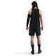 En person med langt mørkt hår kigger væk og er iført en Nike Dri-FIT Running Tank Top, Herre, Black/Reflective Silver, sammen med sorte shorts, sokker, sko og et sort ærme på venstre arm mod en almindelig hvid baggrund.