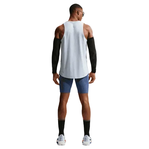 En person står med ryggen til kameraet iført en hvid ærmeløs skjorte, sorte ærmer, blå shorts over Nike Dfadv Aroswft Bf Htight (Game Royal/Diffused Blue/Obsidian/Black), sorte sokker, hvide sneakers og solbriller på en almindelig hvid baggrund.