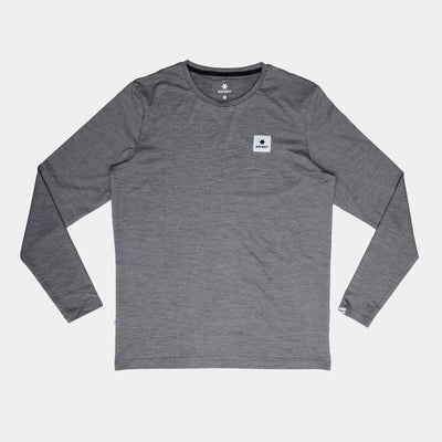 Saysky Statement Pace Long Sleeve, Herre, Grey er lagt fladt på en hvid baggrund. Den har en lille firkantet patch med et sort symbol på venstre bryst - ideel til træning eller som dit nye langærmede basisprodukt.