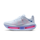 Nike Vomero Premium Dame-sneakeren i Blue Tint/Deep Royal Blue-Aluminium har et hvidt design med blå detaljer, pink detaljer på sålen og en kraftig ZoomX-skummellemsål, vist på en almindelig lys baggrund.
