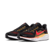 Nike Pegasus 41 Herre i Black/Bright Crimson-Topaz Gold har en sort overdel med røde og gule detaljer, en rød swoosh og en hvid sål - ideel til løbetræning. Vist på en almindelig hvid baggrund.
