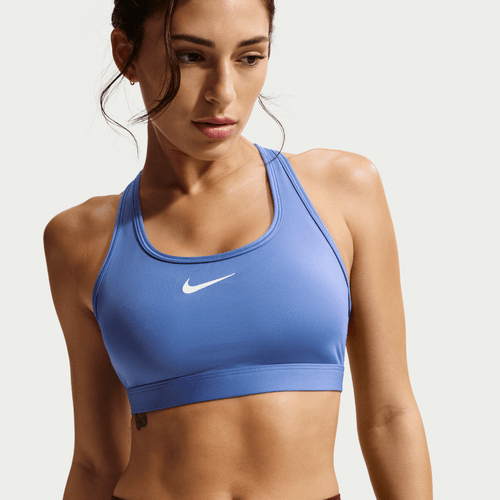 En kvinde bærer Nike Swoosh Medium Sports Bra til kvinder i Sapphire/White. Hun kigger lidt til siden med håret bundet tilbage, et par løse tråde indrammer hendes ansigt, mod en almindelig lys baggrund.