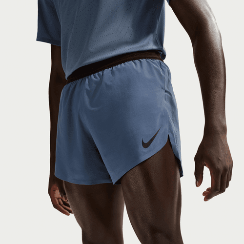 En mand iført blå Nike AeroSwift 4In Brief-Lined Running Shorts (Herre, Diffused Blue/Black), vist fra taljen til midt på låret, står på en almindelig lys baggrund.