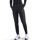 En kvinde iført sorte Nike Dri-FIT Mid-Rise Running Pants (Black/Reflective Silver), en sort langærmet top og hvide Nike-sneakers står med hænderne i lommerne mod en hvid baggrund. Perfekt træningstøj dame-stil.