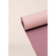 Casall Yoga Mat Position 4mm i Light Pink/Pink, designet til unisex-brug, er delvist rullet ud på en neutral baggrund og afslører sit subtile strukturerede mønster på både den rullede og den flade del.