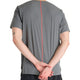 En person står med ryggen til kameraet og foldede hænder iført New Balance Race Day Ulitra Light T-Shirt til mænd i Urgent Red med et gråt kortærmet design med en lodret rød linje og med en tatovering på venstre overarm.