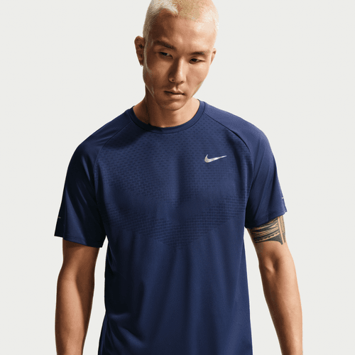 En person med kort platinblondt hår er iført Nike Stride SS Running Top, Herre, Midnight Navy/Reflective Silv, med et lille hvidt Nike-logo på venstre bryst. Baggrunden er helt hvid.