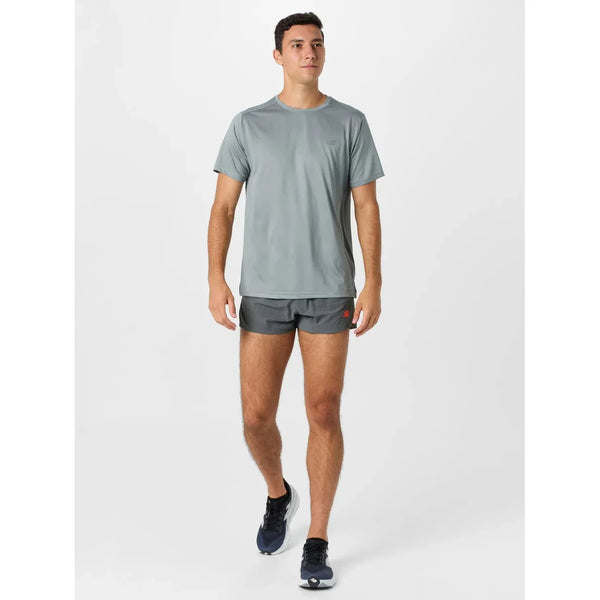 En mand iført en lysegrå atletisk T-shirt, New Balance RC Ultra Light Split Short 3" i Urgent Red og sorte løbesko går fremad mod en almindelig hvid baggrund.