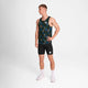 En mand poserer på en almindelig hvid baggrund iført en Saysky Flower Combat Singlet, Herre, Blue Aop, sammen med sorte, tætsiddende shorts, hvide sokker og hvide sneakers. Han har en hånd på hoften og kigger til siden.