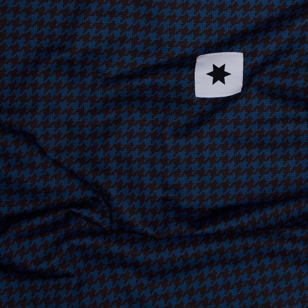 Nærbillede af blåt og sort houndstooth-stof fra Saysky W Houndstooth Combat Singlet (Dame, Blue Aop) med et hvidt rektangulært mærke med en sort stjerne i øverste højre hjørne.
