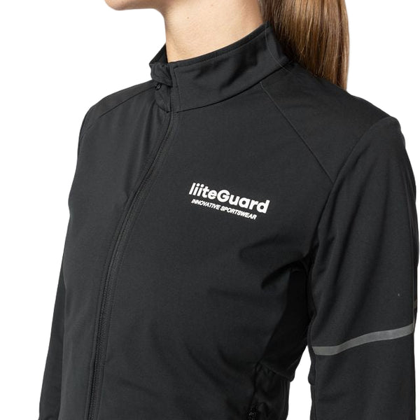 En person bærer en sort Liiteguard Hydro-Tech løbejakke til kvinder med "Liiteguard" i hvidt på brystet, en høj krave, vandafvisende stof, en reflekterende stribe på ærmet og et slankt design på en hvid baggrund.