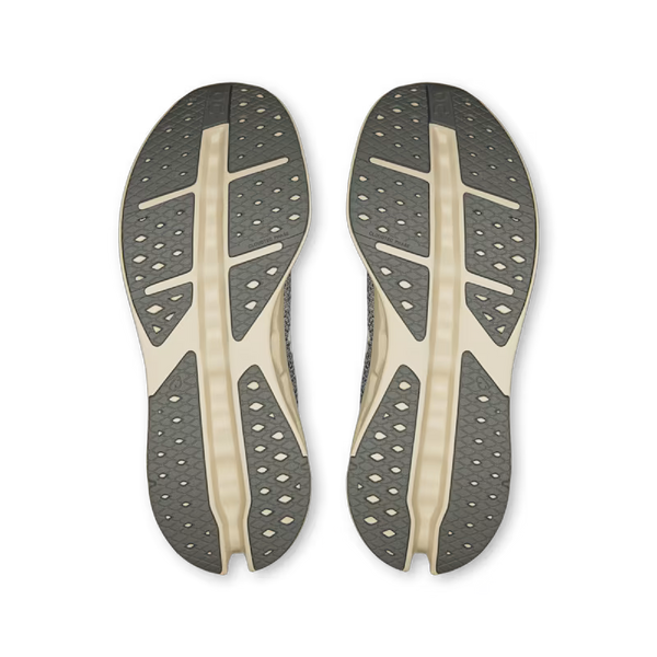 Sålerne på On Cloudsurfer Max, Herre, Asphalt/Ice er vist nedefra og har en grå base med cremefarvede støttelinjer og flere trekantede ventilationshuller for maksimal komfort.