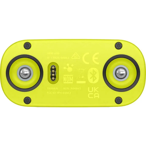 Nærbillede af undersiden af det lysegule Garmin HRM 600 M-XL Pulsmålere (Unisex), der viser to metalkontakter, et centralt firebenet stik og certificeringsmærker, herunder CE-, Bluetooth- og pulsmålingssymboler.