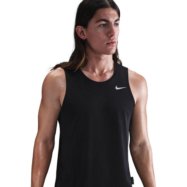 En person med langt brunt hår bærer en sort/reflekterende sølv Nike Dri-Fit Running Tank Top, Herre, og kigger ud til siden mod en hvid baggrund.