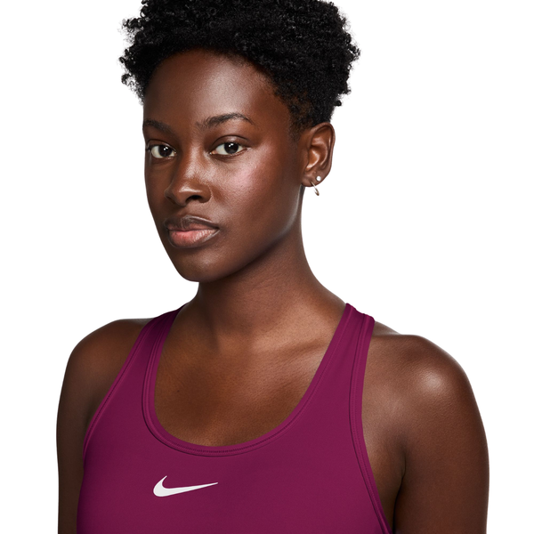 En kvinde iført en Nike-sport-BH med polstring, modellen Dame, i farven True Berry/White, med et bærfarvet design med polstring og et hvidt Swoosh-logo.