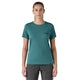 En kvinde står med ansigtet fremad i en Patagonia W's Cap Cool Daily Graphic Shirt, Dame, 73 Skyline/Wetland Blue X-Dye med UPF-beskyttelse og mørkegrå bukser på en almindelig hvid baggrund.