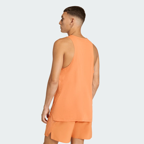 En mand står med ryggen til kameraet iført en orange Adidas Adi365 Singlet, Herre, Duor. Baggrunden er ensfarvet og lys.