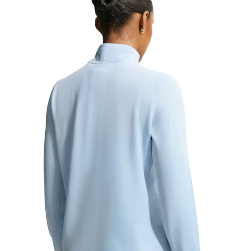 En person ses bagfra iført Nike ACG Half Zip Running Top til kvinder i Hydrogen Blue/Summit White, der har en mock neck-krave og er stylet med en pæn knold på en almindelig hvid baggrund.