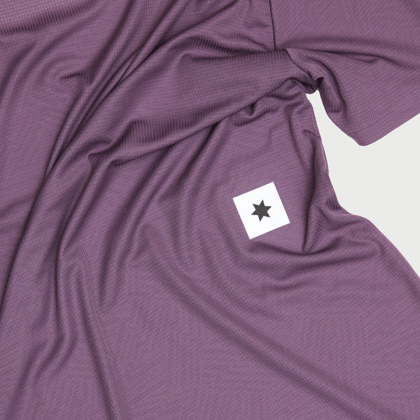 Saysky Reactive Flow Singlet, Herre, Purple Aop har et lilla tekstureret stof og en lille hvid firkantet patch med en sort stjerne, vist fladt med synlige folder og rynker.