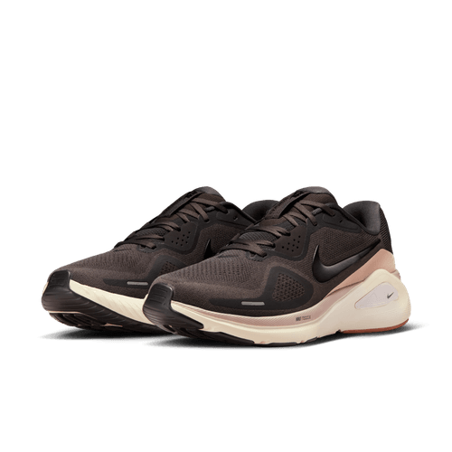 Et par Nike Structure 26 herre løbesko i Medium Ash/Black-College Grey med sorte swooshes, lys beige mellemsåler og sorte ydersåler er sat skråt på en almindelig lys baggrund for at fremhæve deres stabilitet.