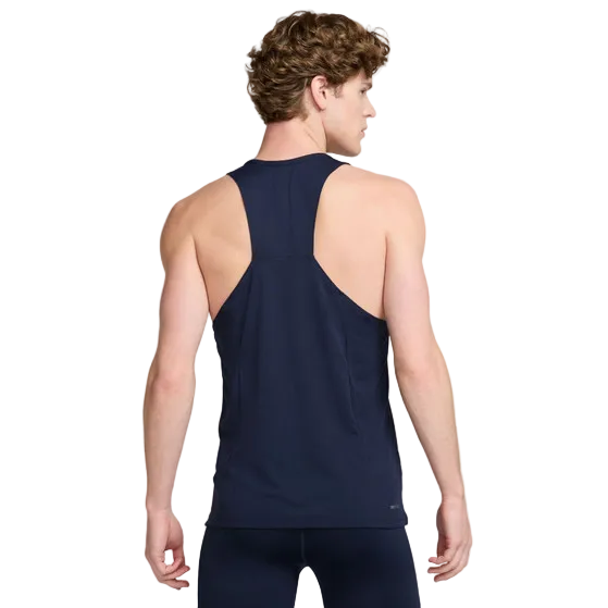 En mand, set bagfra, er iført en Nike Fast Dri-FIT Running Singlet til mænd i Obsidian/Reflective Silver med matchende atletiske leggings. Singletten er lavet af åndbart materiale. Baggrunden er ensfarvet og lys.