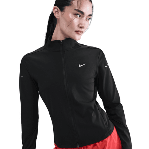 En kvinde i sort Nike Dri-FIT Full-Zip Running Mid Layer (Dame, Black/Reflective Silv) og røde bukser står på en hvid baggrund og ser venstre-ideel løbetøj dame ud til enhver løbetur.