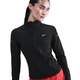 En kvinde i sort Nike Dri-FIT Full-Zip Running Mid Layer (Dame, Black/Reflective Silv) og røde bukser står på en hvid baggrund og ser venstre-ideel løbetøj dame ud til enhver løbetur.