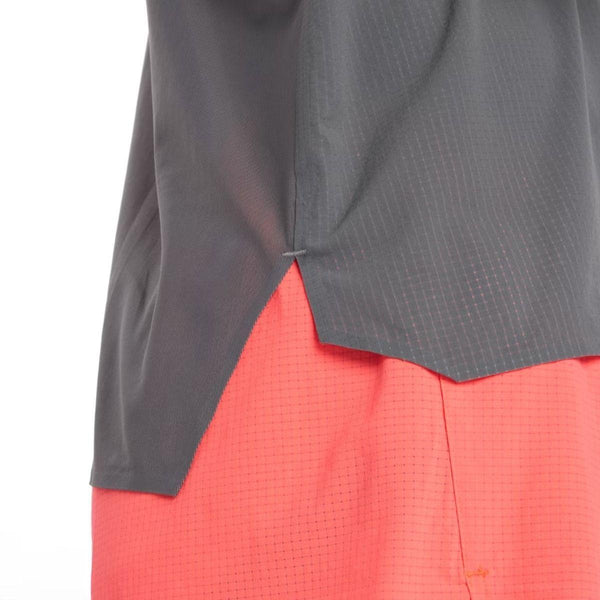 Nærbillede af en person iført New Balance Race Day Ultra Light Singlet til mænd i Urgent Red; kun den nederste del af singletten og de øverste shorts er synlige mod en almindelig hvid baggrund.