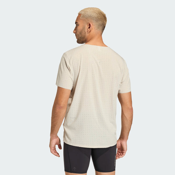 En mand med kort, lysblondt hår ses bagfra iført en Adidas Adi365 Hk Tee, Herre, Putgre og sorte sportsshorts, begge lavet af åndbart materiale, stående mod en almindelig lys baggrund.
