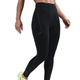 En person viser Nike Therma-FIT ADV High-Waisted 7/8 Reflective Running Leggings til kvinder i Black/Dk Smoke Grey sammen med lysegrønne løbesko mod en hvid baggrund. Kun underkroppen er synlig.