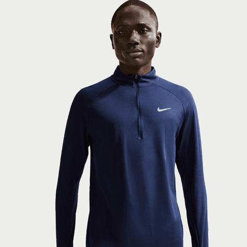 En person står på en ensfarvet baggrund iført Nike Stride Half Zip Midlayer Running Top til mænd i Midnight Navy/Reflective Silver.