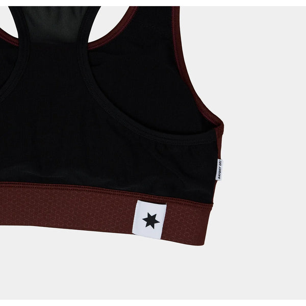 Et nærbillede af Saysky W Logo Combat Sports Bra til kvinder i rød og sort med et hvidt mærke med en sort stjerne på det rødbrune bånd og et lille mærke i siden. Racerback-designet er ideelt til højintensiv træning. Baggrunden er almindelig hvid.