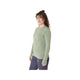 En kvinde med krøllet hår bærer Asics Road Seamless LS Top, Dame, i Monument Blue/Whisper Green med mørke bukser, mens hun står på en almindelig hvid baggrund og kigger til siden. Toppens åndbare design sikrer komfort under aktivitet.