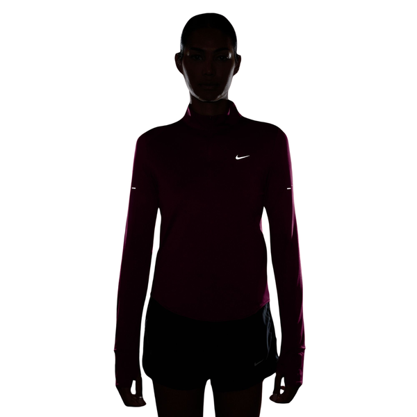 En silhuet af en person iført en Nike Swift Half Zip-løbetrøje, Dame, True Berry/Reflective Silver, samt shorts.