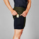 En person i Saysky 2 in 1 Pace Shorts 5", Herre, Green og en mørk skjorte putter en energibar i en sidelomme på shortsene.