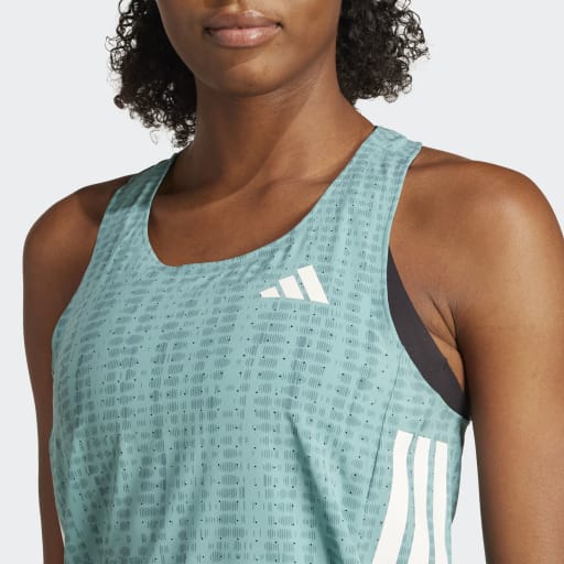 En person med krøllet hår er iført en Adidas Adizero Singlet, Dame in Powtea/Pretea, en let løbesinglet med hvide striber og et lille hvidt logo på brystet. Baggrunden er almindelig lysegrå.