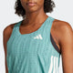 En person med krøllet hår er iført en Adidas Adizero Singlet, Dame in Powtea/Pretea, en let løbesinglet med hvide striber og et lille hvidt logo på brystet. Baggrunden er almindelig lysegrå.