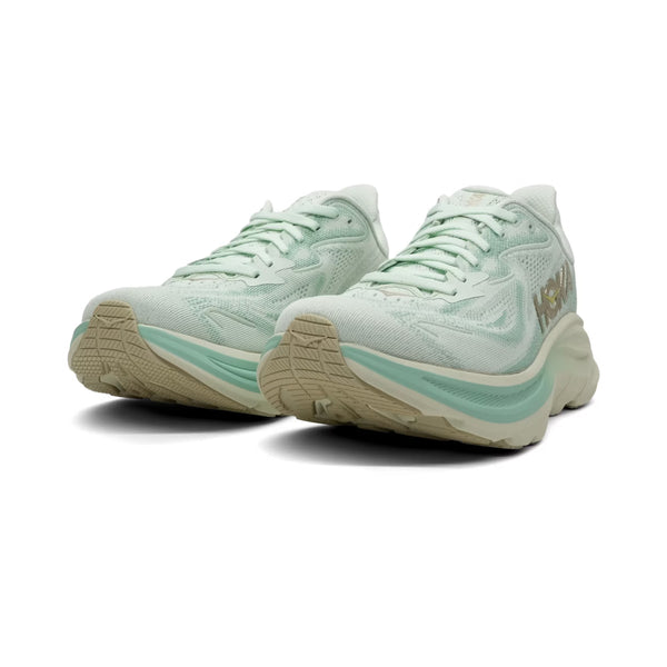 Et par Hoka Clifton 10 løbesko dame i Sea Glass/Jadeite med beige såler, mesh-overdel og det gule HOKA-logo på siderne, vist på en hvid baggrund.