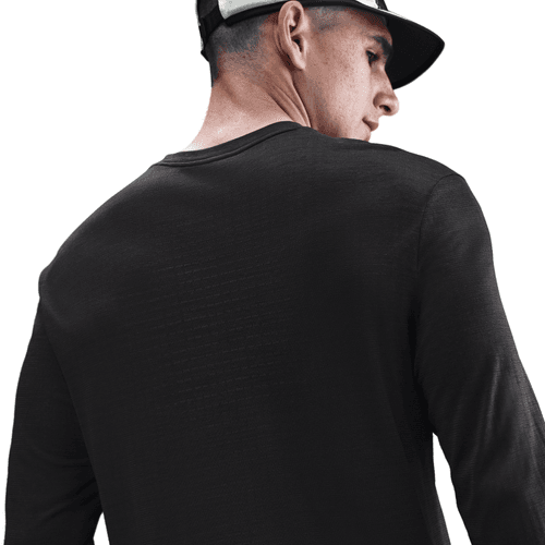 En mand iført Nike Dri-FIT ADV Wool Long-Sleeve Running Top i Black/Anthracite og en sort-hvid kasket ses bagfra på en hvid baggrund, mens han kigger til højre.
