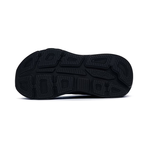 Billedet viser den sorte gummiydersål på Hoka Bondi 9 Dame i Black/Black, som har forskellige slidbanemønstre og teksturerede områder, der giver greb og støtte. "Hoka" er præget på højre side af sålen.